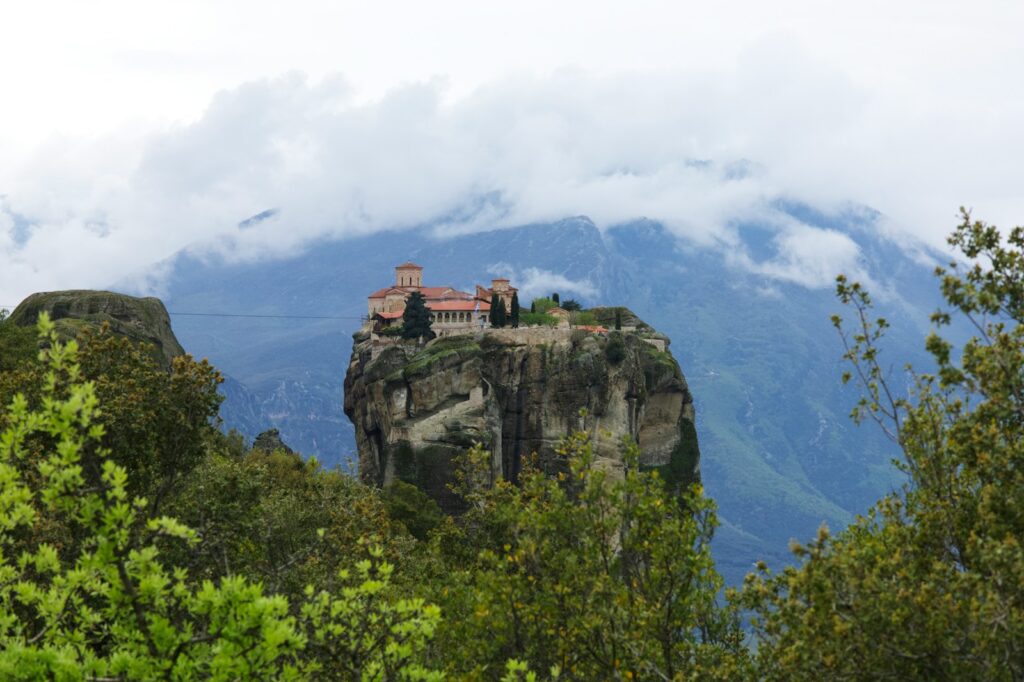 a castle perched on top of a cliff surrounded by trees