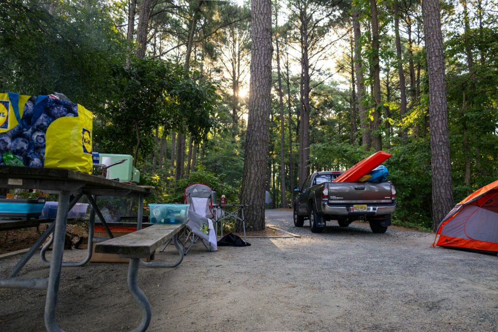 A truck parked next to a tent in the woods.