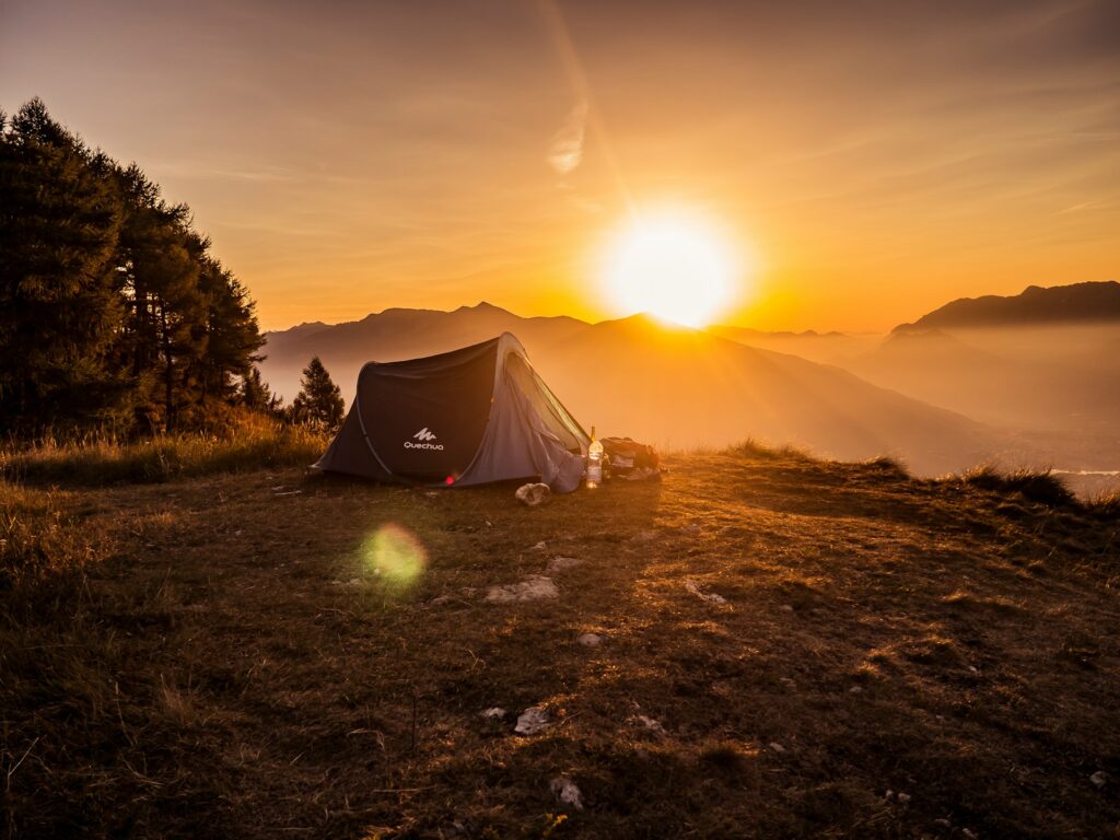Dome tent on mountain top with sun as background photo.