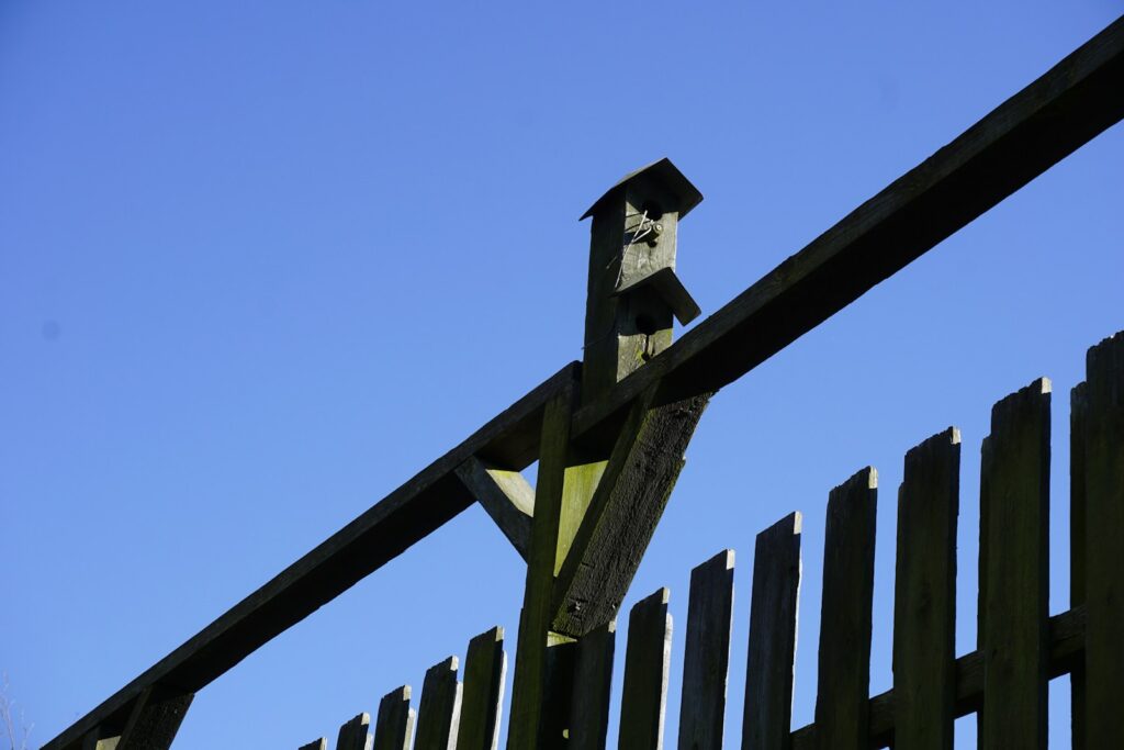 A wooden fence with a birdhouse on top.