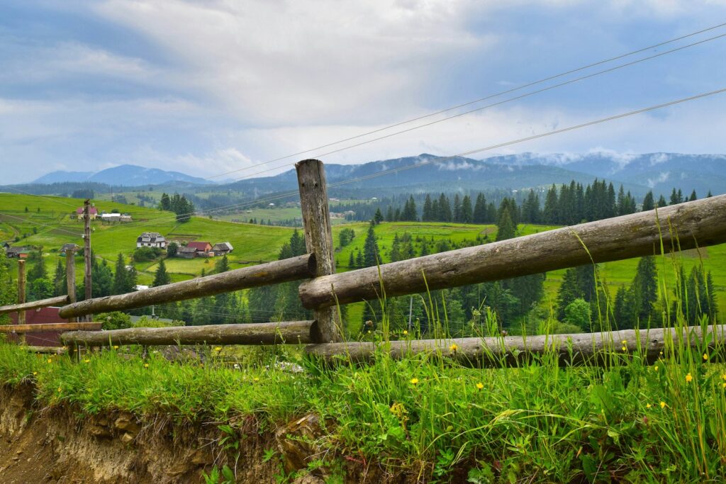 a wooden fence in the middle of a lush green field