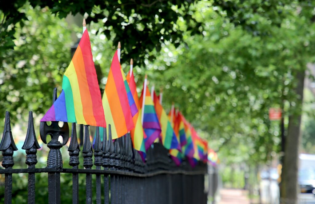 a row of colorful flags on a black fence