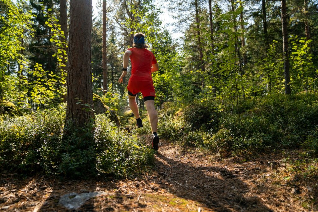A man in red running through a forest.