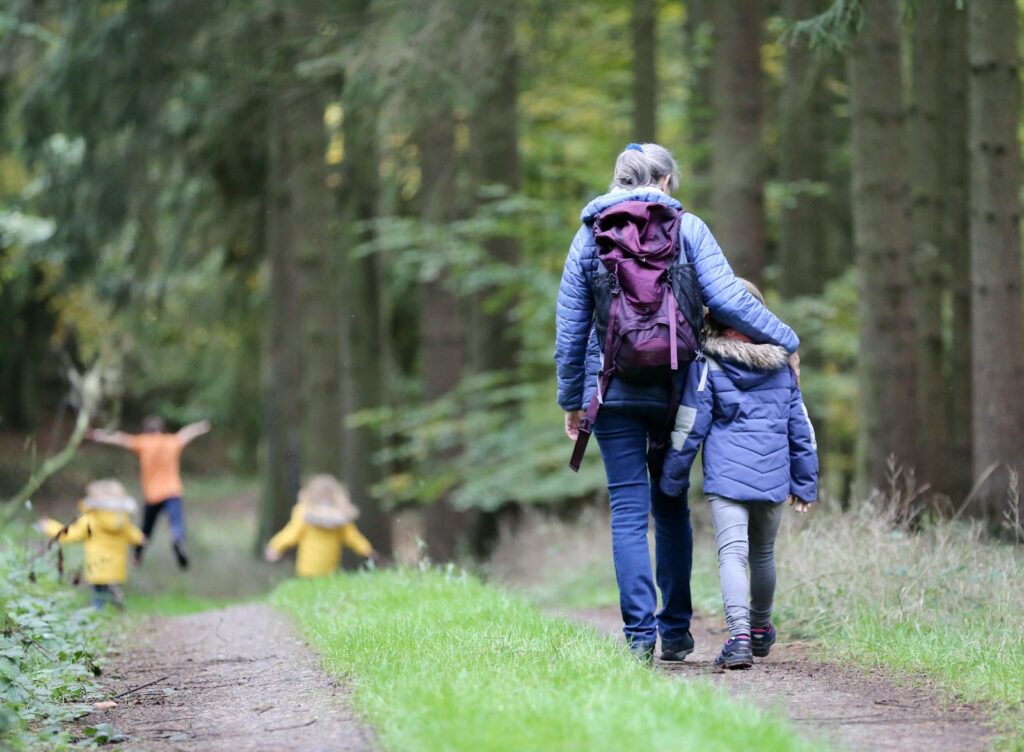 Woman in blue denim jeans and black jacket walking with woman in green jacket.