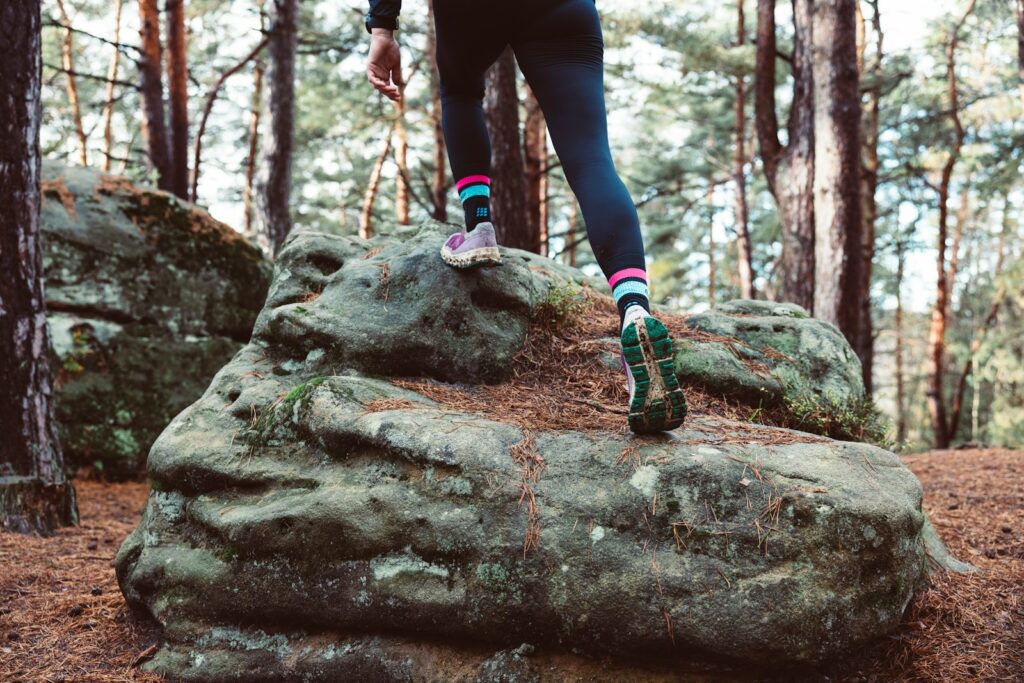 A person walking on a rock in the woods.