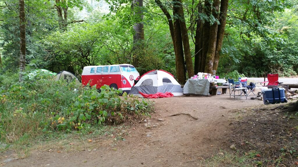 A scenic view of a camper van and tent set up in a tranquil forest, inviting outdoor adventure and relaxation.