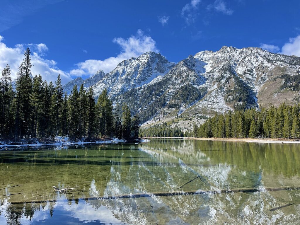 Majestic Grand Teton mountain range reflected in a serene lake, showcasing nature's beauty and tranquility.