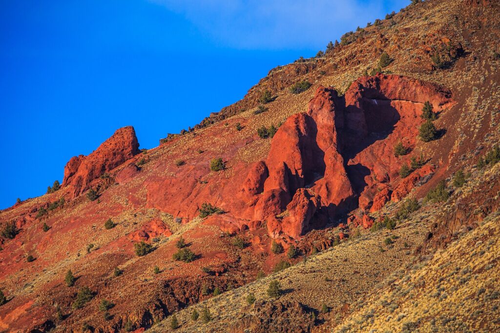 A vibrant red mountain featuring a clock tower, prominently located in Hart Mountain National Antelope Refuge, Oregon.