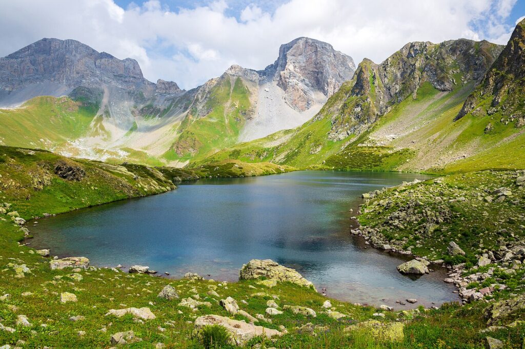 Tranquil Caucasus mountain lake framed by vibrant green grass, reflecting the beauty of nature's untouched landscape.